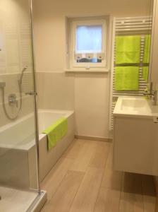 a bathroom with a shower tub and a sink at Freistehendes Ferienhaus Mit Südbalkon in Marktrodach