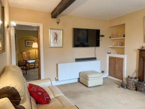 a living room with a couch and a flat screen tv at Yew Tree Cottage in Old Brampton