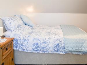 a bed with a blue and white comforter and pillows at Christine Cottage in Flamborough