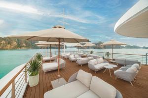 a deck on a yacht with white furniture and umbrellas at Bhaya Soul Cruise in Ha Long