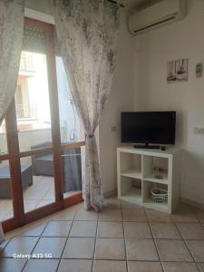 Una sala de estar con televisión y una ventana. en Centrale in Tropea, en Tropea