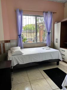 a bedroom with a bed with purple curtains and a window at Casa Albacora in Puerto Baquerizo Moreno