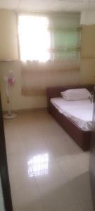 a small bedroom with two beds and a window at Comfort Zone Furnished Apartments 2 in Freetown