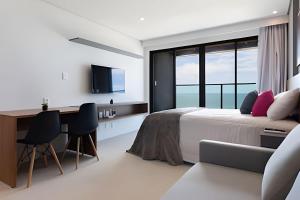 a bedroom with a bed and a desk at ART STUDIO VISTA Mar FRONTAL ARMAÇAO PITUBA in Salvador