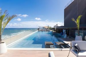 a swimming pool with a view of the ocean at ART STUDIO VISTA Mar FRONTAL ARMAÇAO PITUBA in Salvador