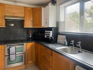a kitchen with wooden cabinets and a sink at Elder Cottage in Bridgend