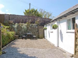 a garden entrance to a white cottage with a wooden fence at Kilcummer Stables in Tintagel