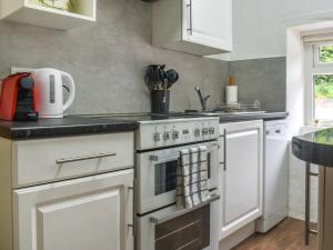 a kitchen with a white stove top oven next to a sink at Bondcroft Farm Cottage in Embsay