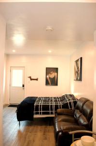 Cozy Bachelor Suite with Kitchenette - Near Downtown في سودبيري: غرفة نوم بسرير واريكة جلدية