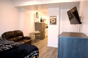 Cozy Bachelor Suite with Kitchenette - Near Downtown في سودبيري: غرفة بسرير واريكة وتلفزيون