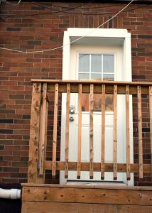 Cozy Bachelor Suite with Kitchenette - Near Downtown في سودبيري: شرفة بها باب أبيض عليه كلب