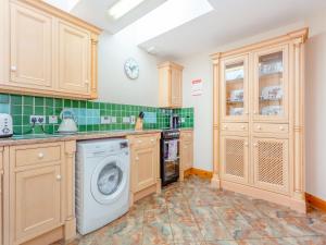 eine Küche mit Holzschränken, einer Waschmaschine und einem Trockner in der Unterkunft Fyvie Cottage in Fort William