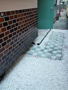 Una pared de ladrillos con suelo de baldosas al lado de un edificio en Smile Guest House, en Higashiōsaka