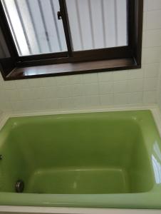Una bañera verde en un baño con ventana. en Smile Guest House, en Higashiōsaka
