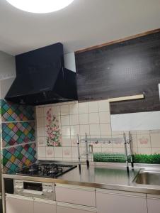 una cocina con fregadero y estufa horno superior en Smile Guest House, en Higashiōsaka