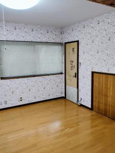 Habitación vacía con suelo de madera y puerta en Smile Guest House, en Higashiōsaka 1 foto más