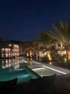 a swimming pool at night with palm trees and buildings at Pyrineus Residence - Resort em Pirenópolis in Pirenópolis