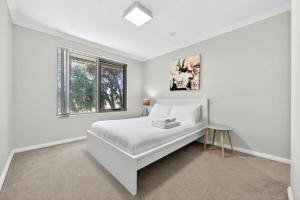 a white bedroom with a bed and a window at Stylish Rockingham Getaway 2BR Coastal Apartment in Rockingham