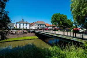 a bridge over a river in front of buildings at Hotel en restaurant Della Contessa in Buren