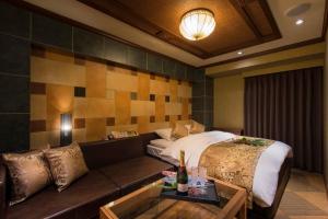 WadaにあるHotelTSUBAKI柏のベッドとソファのあるホテルの部屋