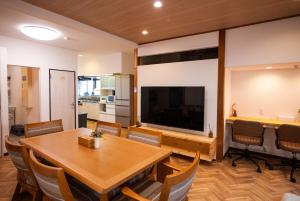 a dining room with a table and a large television at たびんちゅの宿 in Toyama