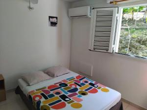 a bed in a room with a window at Maison charmante à Rivière-Pilote avec vue sur la montagne in Rivière-Pilote
