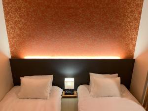 two beds with white pillows in a hotel room at おおさか城北 宿福 in Osaka +36 photos