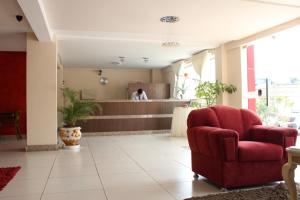 a lobby with a red chair and a counter at Hotel Central in Vitória da Conquista