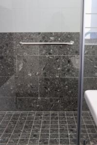 a bathroom with a shower with black tiles at The Essenwood Collection in Durban +69 photos