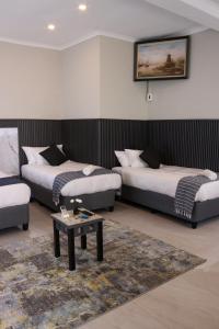 a room with two beds and a table in it at The Essenwood Collection in Durban