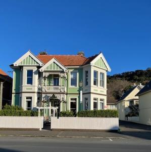 a green and white house with a white fence at Sahara Guest House in Dunedin