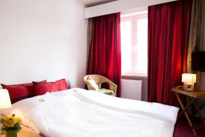 1 dormitorio con cama blanca y cortinas rojas en Hotel Oymanns, en Hamberge