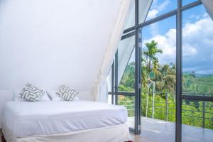a bedroom with a bed and a large window at Sinharaja River Lodge in Nikawatawana
