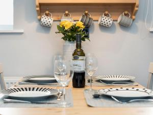 einen Tisch mit einer Flasche Wein und Gläsern in der Unterkunft Crescent Cottage in Askham