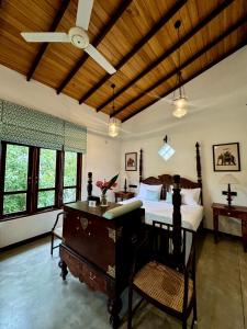 a bedroom with a bed and a desk and windows at Villa Samas in Galle
