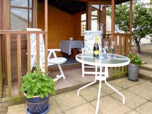 a patio with a table and two chairs and a bottle of wine at The Old Coach House in Burythorpe +6 photos