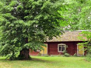 a log cabin with a tree in front of it at 11 person holiday home in STORA SUNDBY in Böcklinge