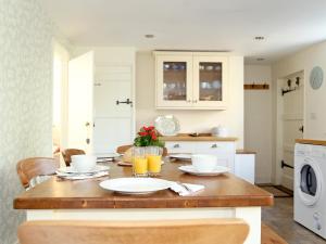 a kitchen with a wooden table with glasses of orange juice at Pilgrim Cottage in Hollingbourne +9 photos