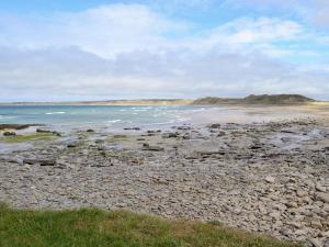 a beach with rocks and the ocean on a cloudy day at Harland Cottage in Castletown