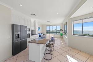 a kitchen with white cabinets and a counter with stools at Alexandra on the Pacific in Mooloolaba