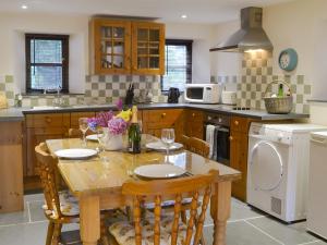 una cucina con tavolo e sedie e una cucina con lavastoviglie di Clematis Cottage a Holsworthy