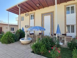 un patio con sillas y sombrillas frente a una casa en Crystal Hotel Bukhara, en Bukhara
