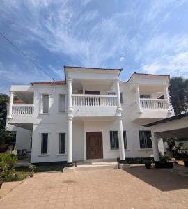 a large white house with a porch and balcony at Heather's Retreat in Brufut