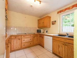 a kitchen with wooden cabinets and a sink and a window at Spacious Wéris forest escape in Weris