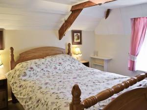 a bedroom with a bed with a floral bedspread at Pillar Box Cottage in Tintagel