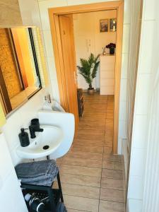 a bathroom with a sink and a mirror and a hallway at City Apartment GL10 in Bergisch Gladbach