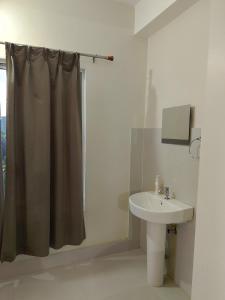 a bathroom with a shower curtain and a sink at Rongo's Riverside Farm Stay in Kumai