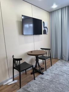 a room with a table and two chairs and a tv at Damir hotel in Aktobe