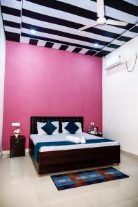 a bedroom with a large bed with a pink wall at Banaras Bloom Residency in Varanasi