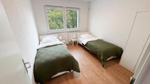 two beds in a small room with a window at Monteurwohnungen mit TV, Internet, Parkplatz, Waschmaschine, Küche, Balkon, Restaurants und Supermarkt in Halle an der Saale
